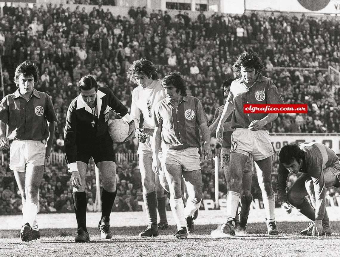 Imagen Un grupo de jugadores de San Lorenzo y Lanús ayuda al árbitro Pestarino a buscar su tarjeta amarilla en el césped.