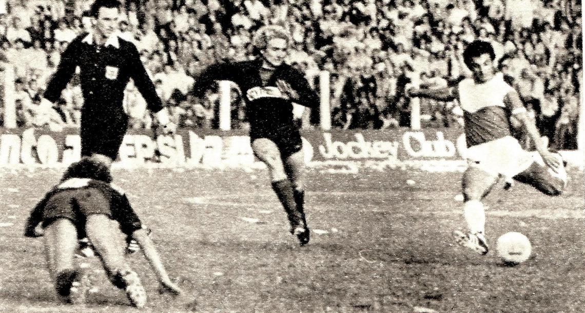 Imagen Nacimiento, volante de Guaraní, se apresta a rematar con Colecchia en el suelo. El árbitro Pasturenzi sigue el juego.