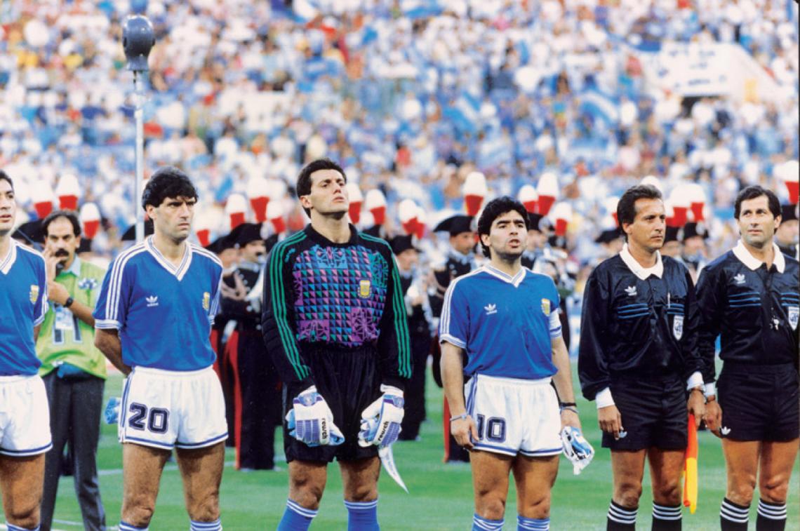 Imagen SERIEDAD mientras suena el himno argentino. Lo acompañan en la imagen Juan Simón y su amigo Diego Maradona.