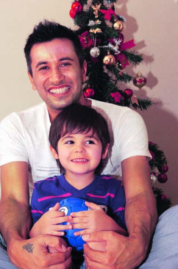 Imagen VALENTINO, de 3 años, y su papá, delante del arbolito de navidad. Los dos son hinchas de Boca.