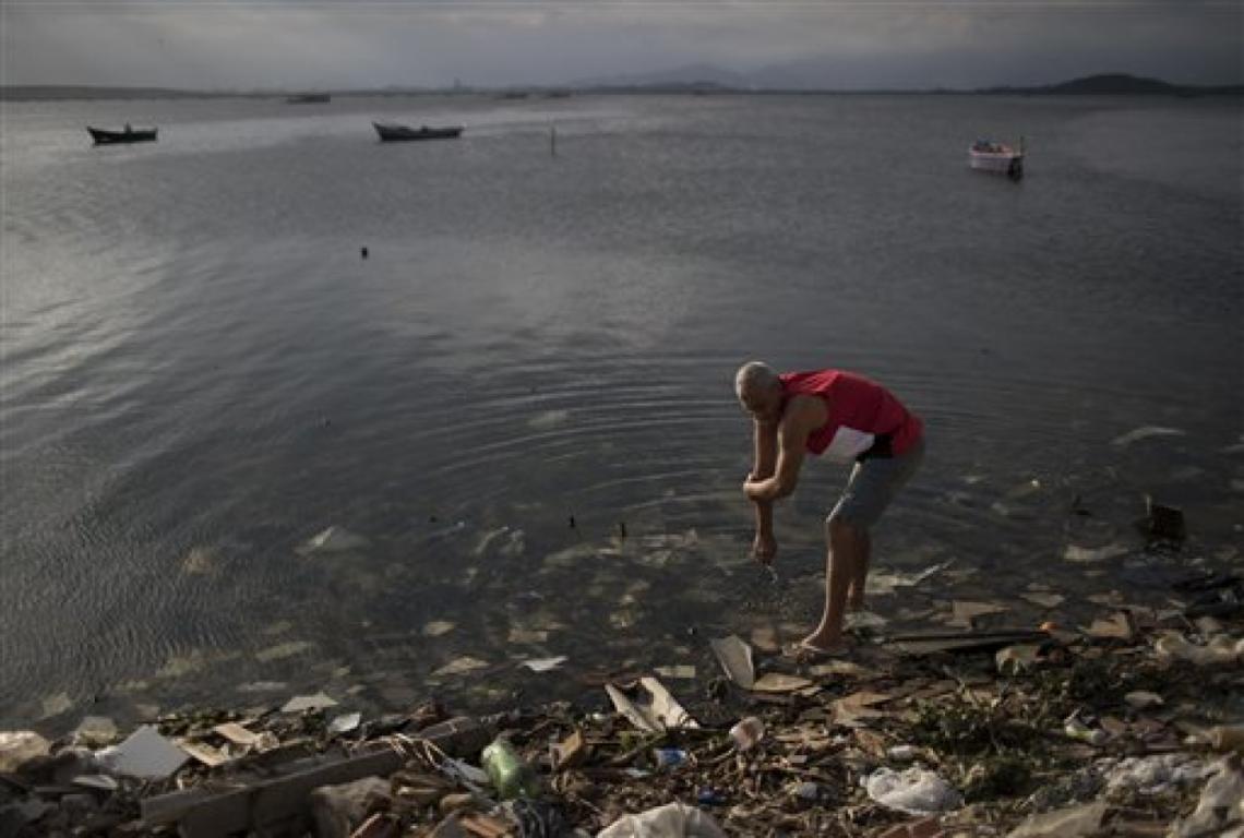 Un hombre se limpia en las aguas contaminadas de la Bahía Guanabara en Río de Janeiro, Brasil, el sábado 30 de julio de 2016. Aunque las autoridades locales, entre ellas el alcalde de Río, Eduardo Paes, han reconocido el fracaso de la ciudad en sus accion