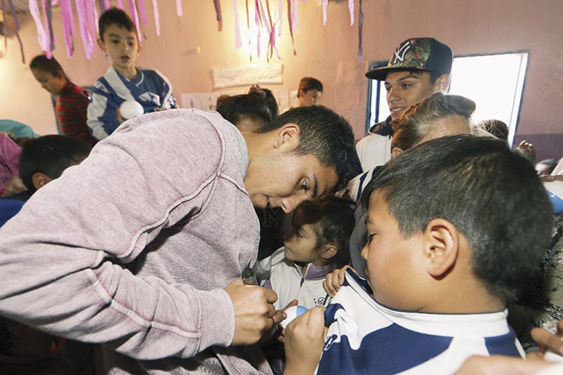 Emanuel Reynoso firmando autógrafos en el comedor solidario "Los bajitos del futuro", donde él también supo pasar cuando era un chico cargado de sueños e ilusiones.