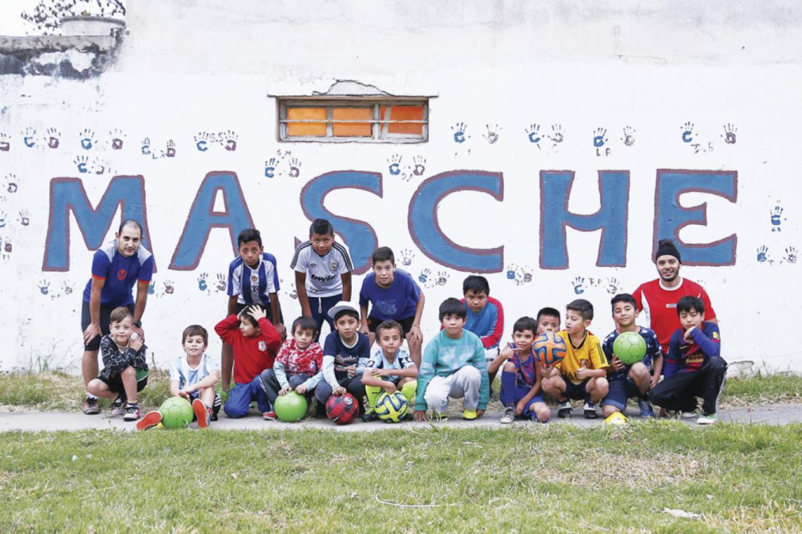 Los chicos y sus entrenadores posan junto al paredón que honra a una de las grandes figuras de la Selección.