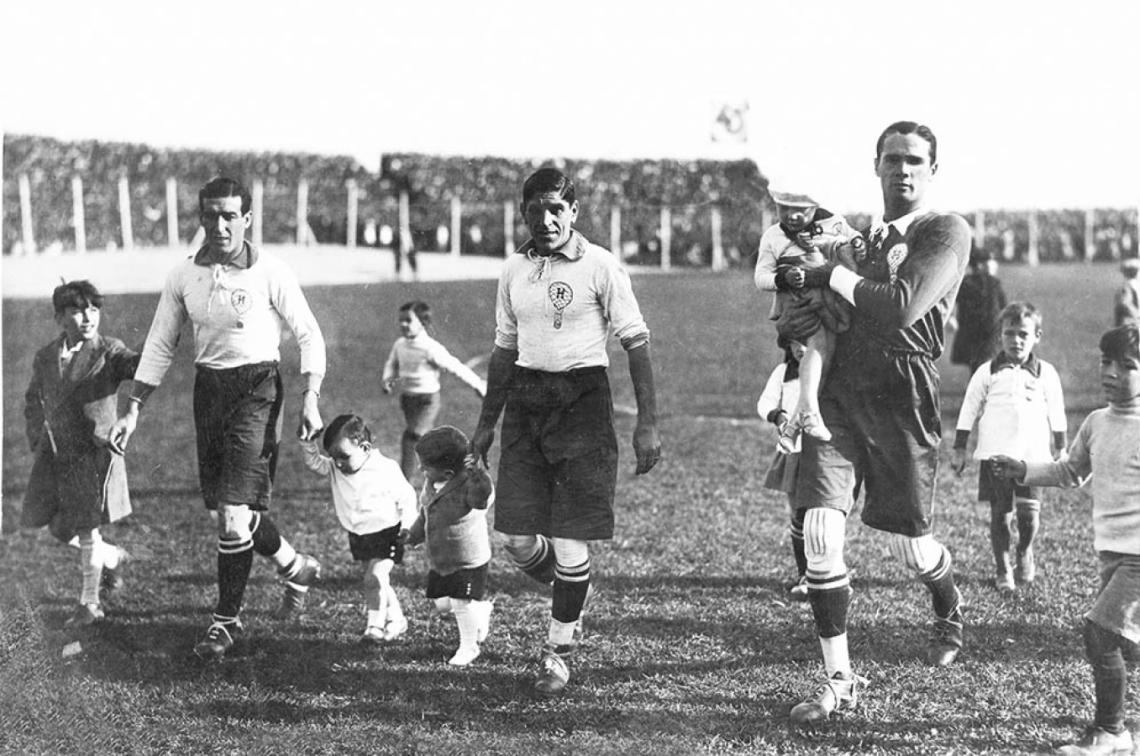 Imagen Huracán de 1928. Onzari, Loizo y Negro ingresan al campo rodeados de mascotas, una costumbre que perdura tanto como el fútbol.