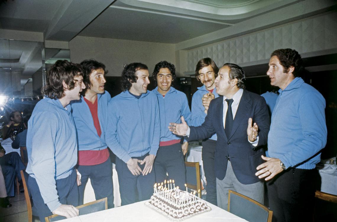 Sonriendo frente a la torta con velitas que sopla el increíble Toto Lorenzo, en la concentración de Boca, entre Ribolzi, Gatti y Sa, y ante la mirada del profe Castelli, en la otra punta.