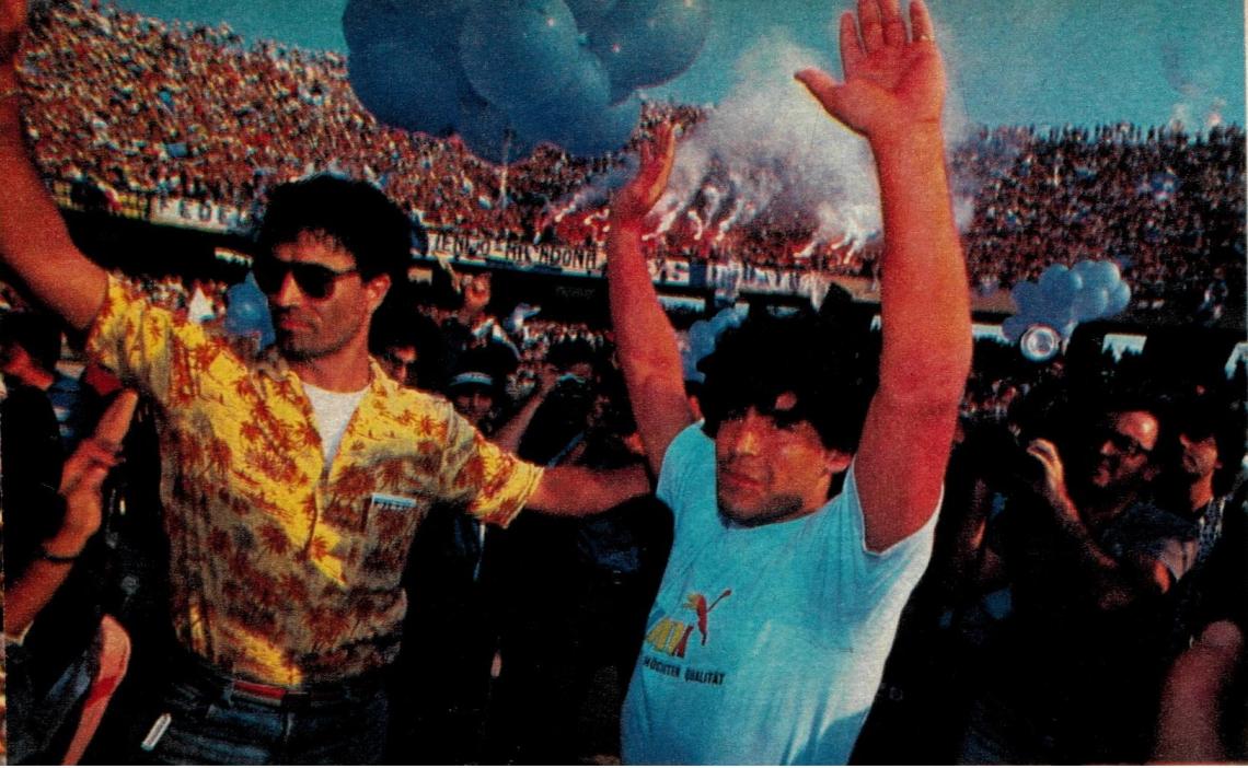 La aparición de Diego en el San Paolo. Jueves 5 de julio a las 18.25 horas. Fuegos artificiales en las tribunas respondiendo a sus brazos en alto.