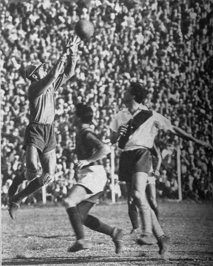 Salta Carrizo para alcanzar le pelota enviada en un tiro libre. La foto permite apreciar la enorme cantidad de espectadores que acudió a presenciar el match y que produjo la recaudación de 185.733,90, lo que constituye nuevo récord para un partido interclubs, Esa multitud observó una conducta ejemplar.