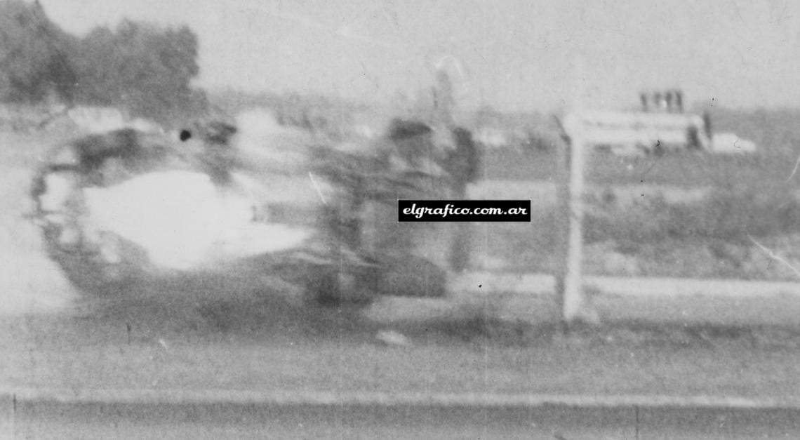 El auto está en el aire y volcando sobre el alambrado. Varios postes han quedado en su camino y en pocos segundos se detendrá en posición invertida.