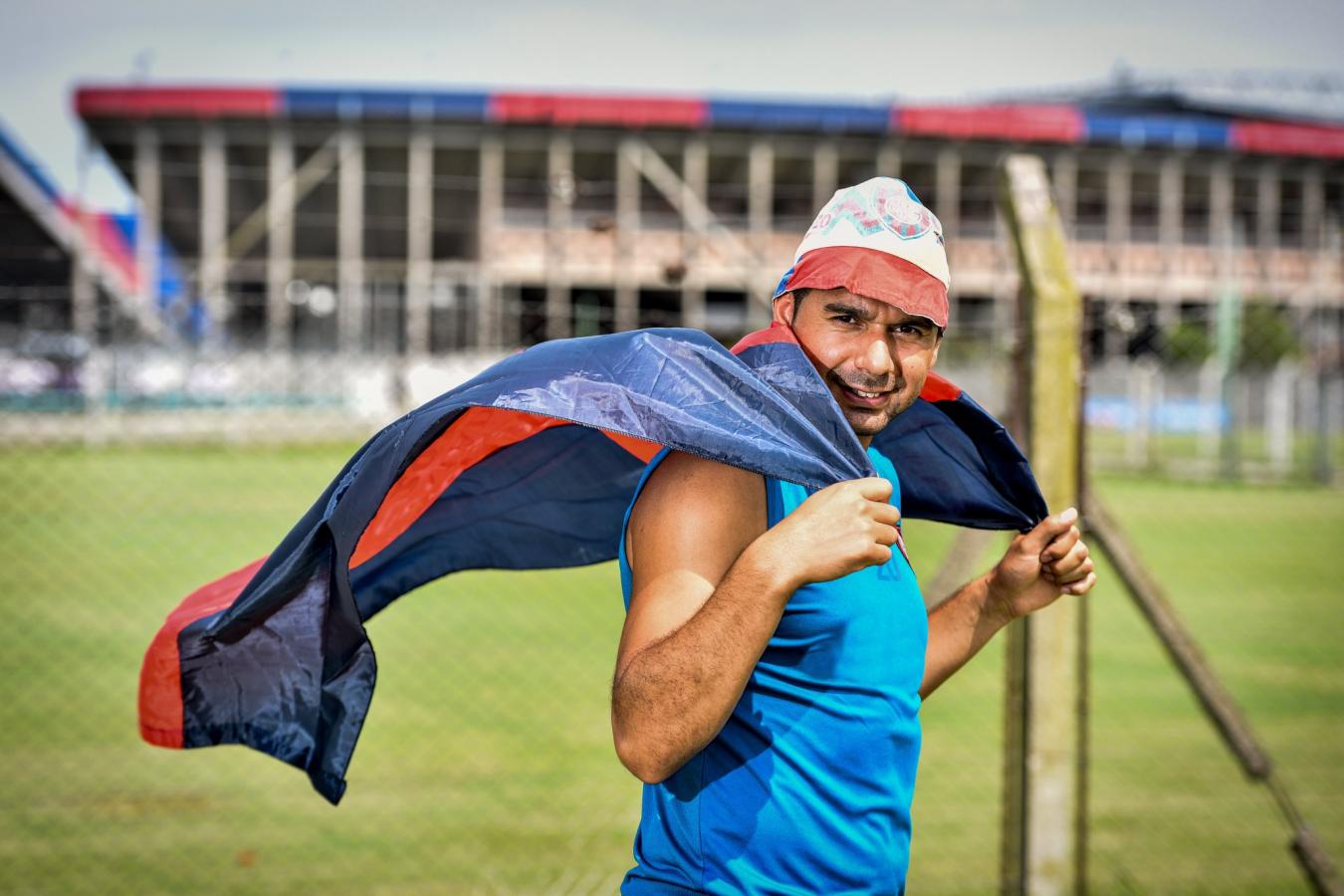 Imagen Ortigoza, como un hincha más, con el gorro piluso, la bandera azulgrana y el Gasómetro de fondo. Foto: @SanLorenzo