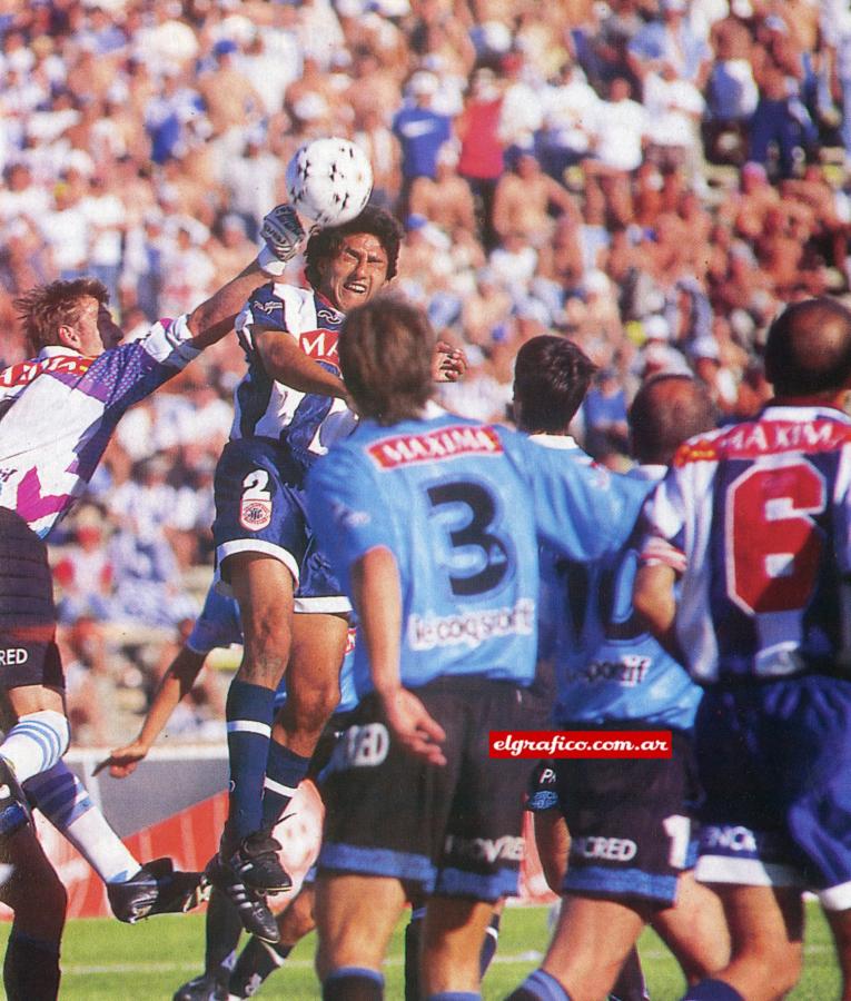 Imagen Centro sobre el área de Belgrano. Bernardo Ragg intenta sacar la pelota con un puñetazo, ante la carga de Ramón Galarza, de Talleres. Detrás, el multitudinario marco.