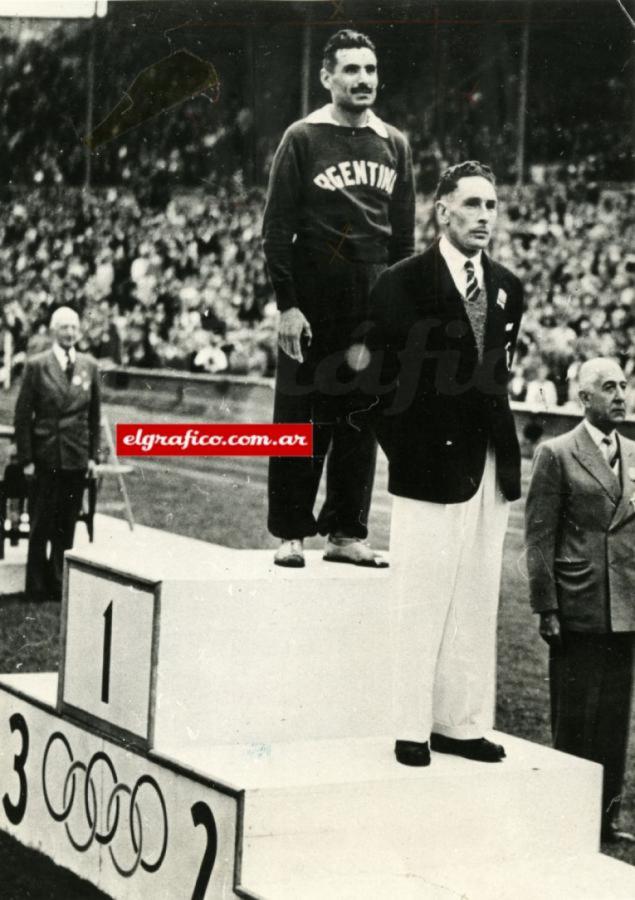 Imagen Delfo en los más alto del podio, mientras suenan las estrofas de la canción patria nacional. Los JJOO de Londres 1948, fue la primer olimpíada donde se tocó el himno de los ganadores de la medalla de oro en la premiación.