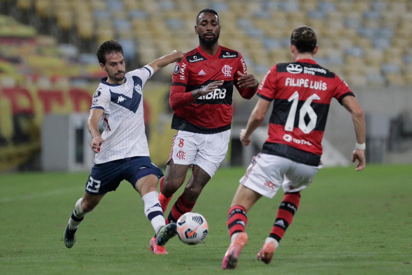 Agustín Bouzat disputa el balón con Gerson y Filipe Luis. Vélez controló la pelota durante varios pasajes del encuentro. Foto: Conmebol