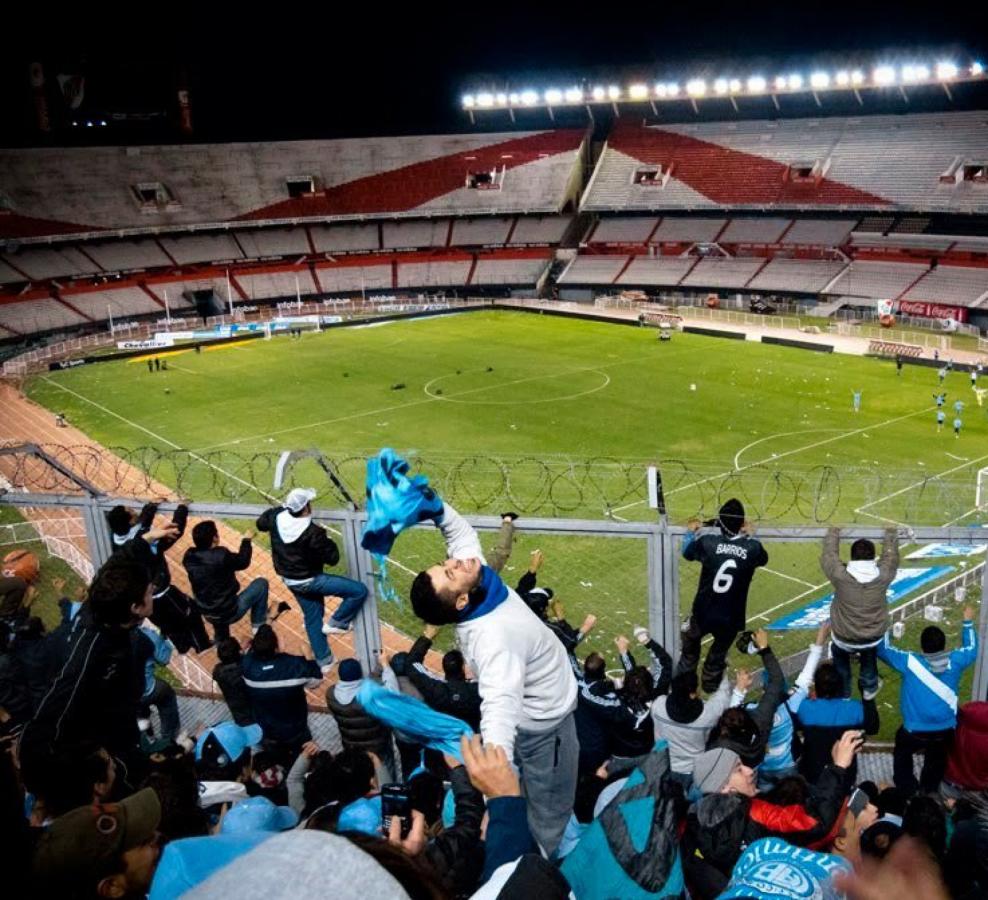 Imagen La parcialidad Pirata festejando en un Monumental vacío, ya de noche. Los jugadores retribuyen el afecto desde el campo. Belgrano era de Primera.